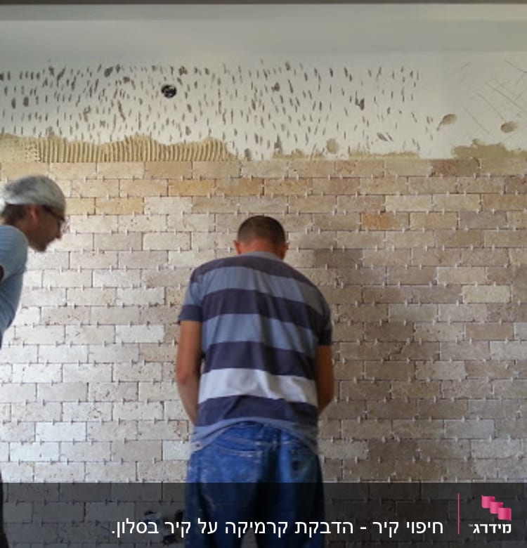 שני אנשים עובדים על קיר לבנים עם כלי עבודה